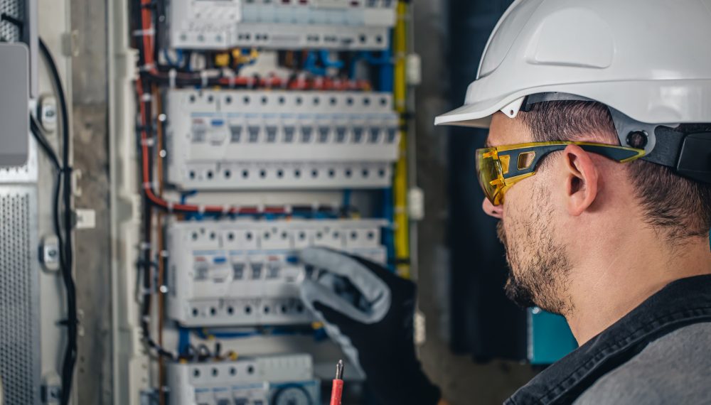 Man, an electrical technician working in a switchboard with fuses. Installation and connection of electrical equipment.